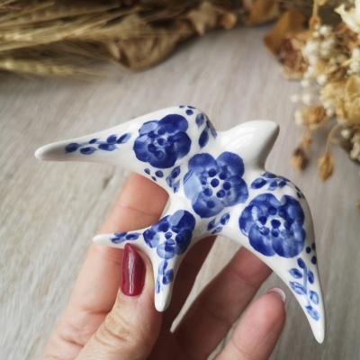 Figura de cerâmica em forma de andorinha com flores azuis.