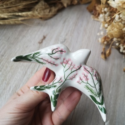 Escultura de pássaro em cerâmica branca pintada com flores verdes e rosa