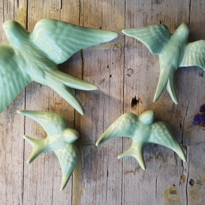 Figuras decorativas de pássaros em cerâmica verde claro sobre madeira rústica