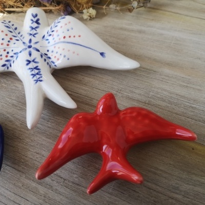 Esculturas de pássaros de cerâmica decorados em várias cores sobre madeira