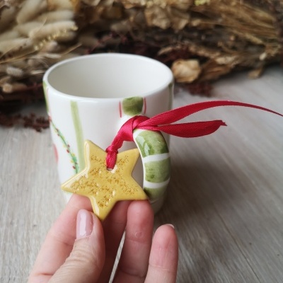 Caneca com pega verde às riscas brancas e pendente de estrela amarela com fita vermelha