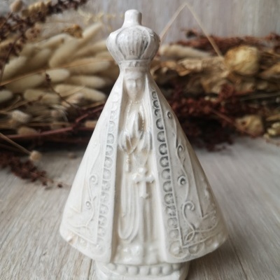 Estátua religiosa branca em cerâmica com manto e coroa, mãos juntas em oração.