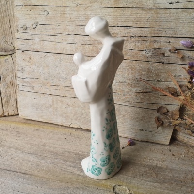 Escultura abstrata em cerâmica branca com manchas verdes sobre madeira