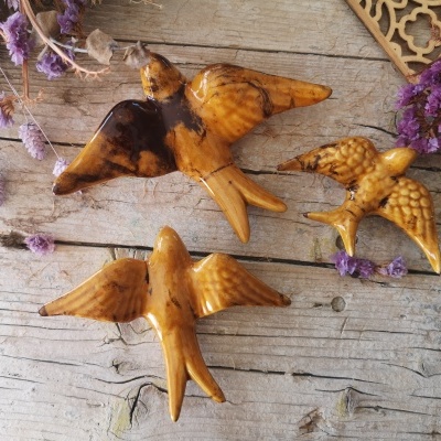 Três aves decorativas em madeira com flores secas lilás sobre fundo rústico de madeira