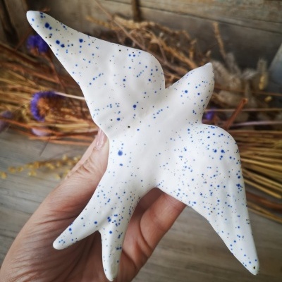 Escultura de pássaro em cerâmica branca com manchas azuis