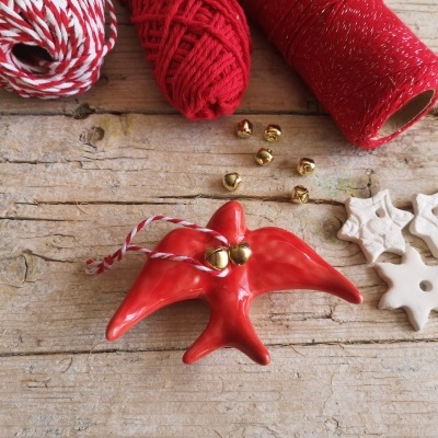 decoração natalícia com estrela do mar vermelha, sininhos dourados, cordas vermelhas e brancas e estrelas brancas de cerâmica