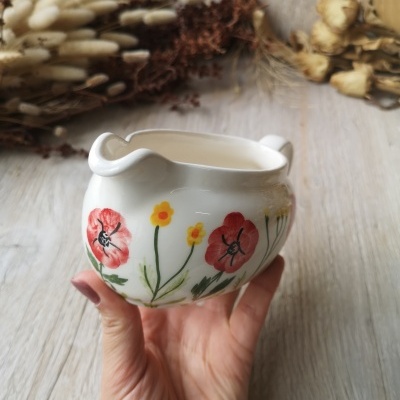 Jarro cerâmico branco com flores pintadas e fundo de flores secas