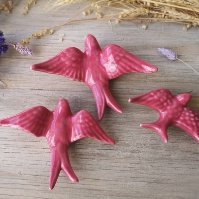Aves decorativas cor de rosa em cerâmica sobre madeira com flores secas