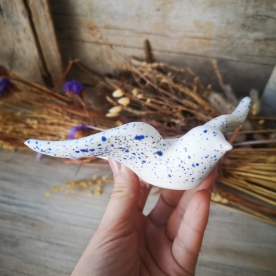 Escultura cerâmica branca com pinturas azuis em forma de pássaro