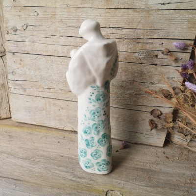 Figura decorativa de cerâmica branca com flores azuis e mulher segurando criança
