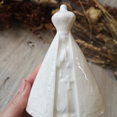 Figura religiosa branca em cerâmica com relevo de mulher coroada e mãos juntas em oração