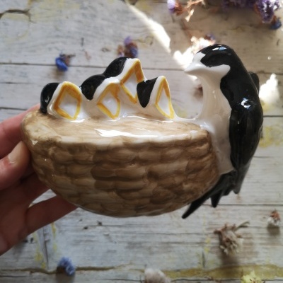 Figurinha decorativa de cerâmica com pássaros num ninho castanho