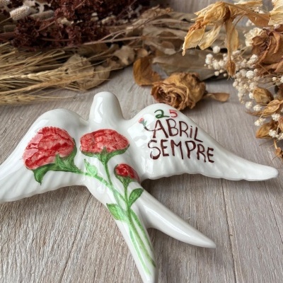 Escultura branca de pássaro com flores vermelhas pintadas e texto em cerâmica