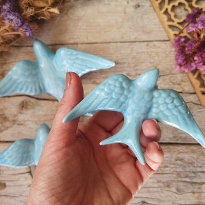 Estatuetas de pássaros azuis em cerâmica com textura detalhada sobre mesa de madeira clara