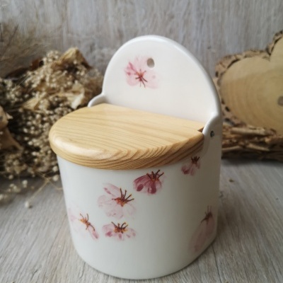 Recipiente branco de cerâmica com tampa de madeira e flores cor de rosa