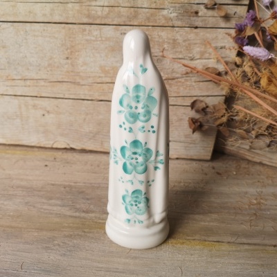 Estatueta cerâmica branca com flores azuis em fundo de madeira rústica e flores secas