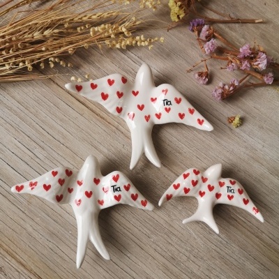 Três pássaros decorativos brancos com corações vermelhos e palavra Tia em superfície de madeira com flores secas
