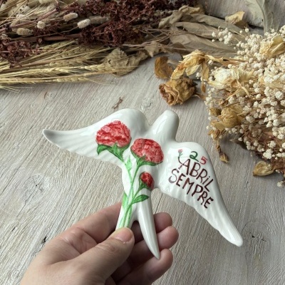 Pomba de cerâmica branca com cravos vermelhos e texto 25 ABRIL SEMPRE