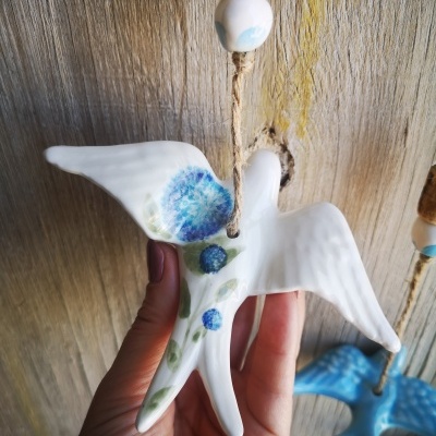 Pendentes cerâmicos em forma de pássaro com pinturas azuis pendurados em corda