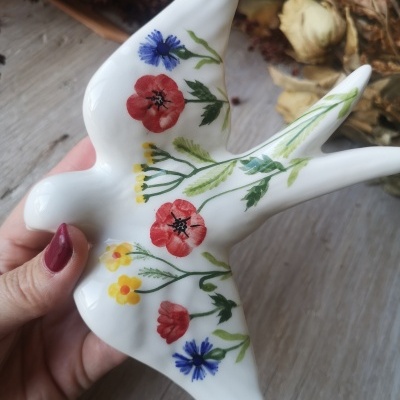 Escultura cerâmica de pássaro com flores coloridas
