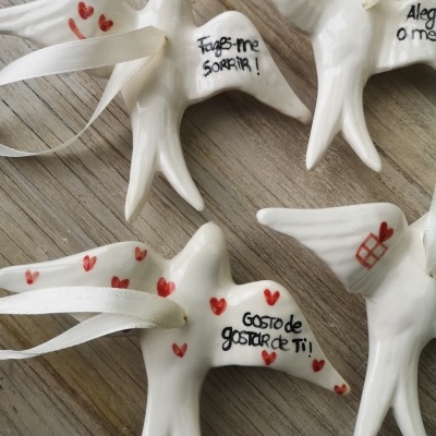 Pássaros decorativos em cerâmica branca com fitas e textos em português