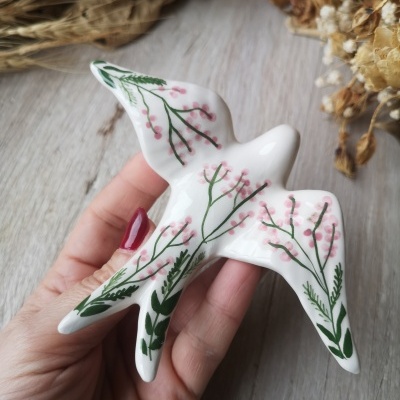 Pássaro em cerâmica decorado com flores e folhas verdes