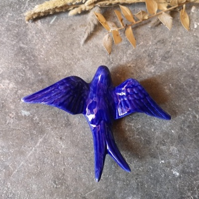 Pássaro decorativo de cerâmica azul e roxo com asas abertas