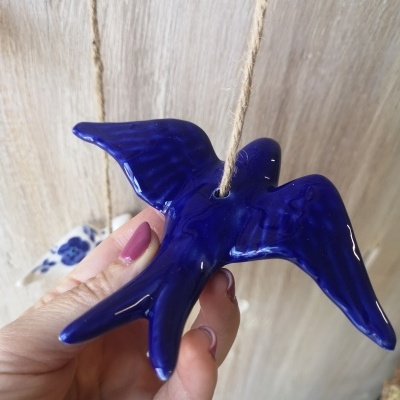 Pássaro de cerâmica azul pendurado por corda de juta