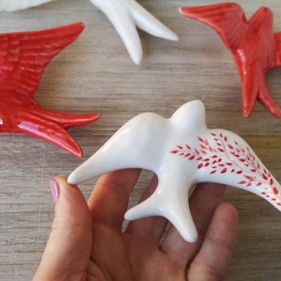 Figuras decorativas de pássaros em cerâmica vermelha e branca com padrão de folhas