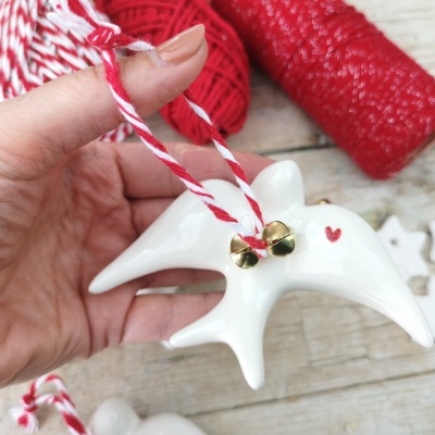 Enfeite de golfinho em porcelana branca com sinos dourados e corda vermelha e branca
