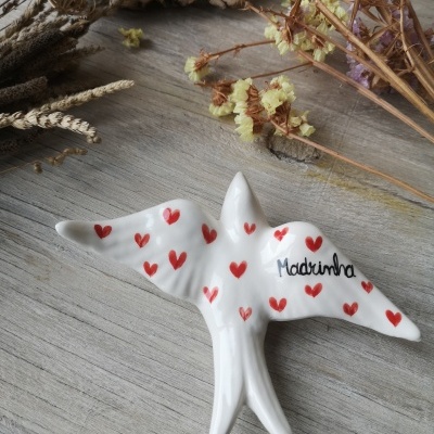 Pássaro de cerâmica branca decorado com corações vermelhos e escrita 'Madrinha'