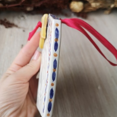 Adorno cerâmico com padrão azul e castanho e fita vermelha