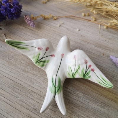 pássaro decorativo em cerâmica branca pintado com flores cor-de-rosa e folhas verdes