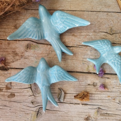 Três pássaros decorativos de cerâmica azul claro sobre madeira envelhecida