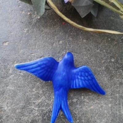 Enfeite de pássaro azul em textura realista sobre chão cinzento