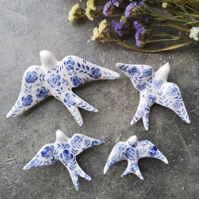 Pássaros decorativos em cerâmica branca com padrão floral azul e flores secas