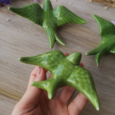 Figuras de pássaros verdes em cerâmica brilhante sobre madeira clara