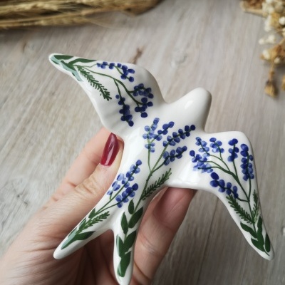 Peça decorativa em cerâmica branca em forma de pássaro com pintura floral azul e verde