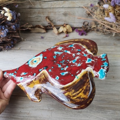 Peixe cerâmico colorido em fundo de madeira com flores secas