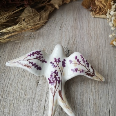 Figura decorativa em porcelana branca em forma de ave com flores roxas e ramos castanhos