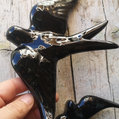 Figura decorativa de duas andorinhas pretas brilhantes contra fundo de madeira clara