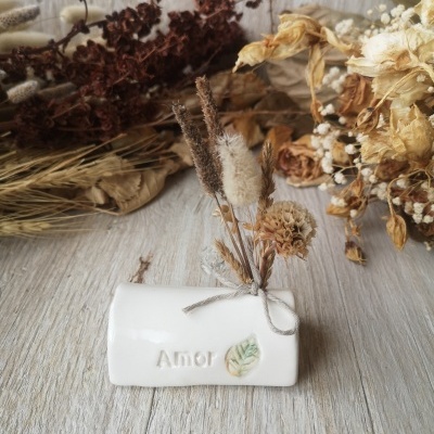 Jarro branco de cerâmica com flores secas e palavra Amor
