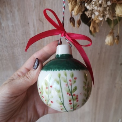 Bola de Natal em cerâmica com folhagem pintada e laço vermelho