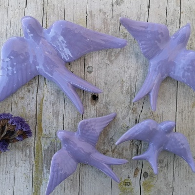 Quatro pássaros lilás em cerâmica sobre madeira envelhecida com flores secas ao lado