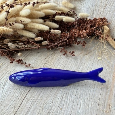 Escultura decorativa de peixe em cerâmica azul com ramos secos ao fundo