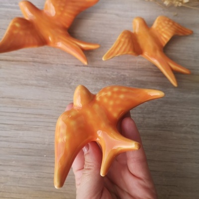Figuras decorativas de pássaros em cerâmica laranja sobre madeira
