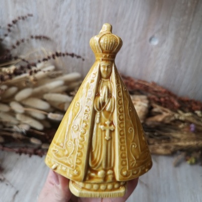 Escultura religiosa amarela em cerâmica com manto e crucifixo