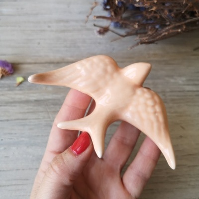 Figura em cerâmica rosa de andorinha com detalhes nas asas