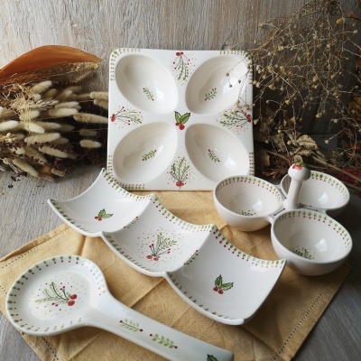Conjunto de louça branca com padrão festivo e bagas vermelhas em mesa de madeira