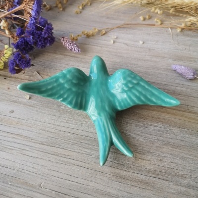 Figura decorativa de pássaro cerâmico turquesa com asas abertas